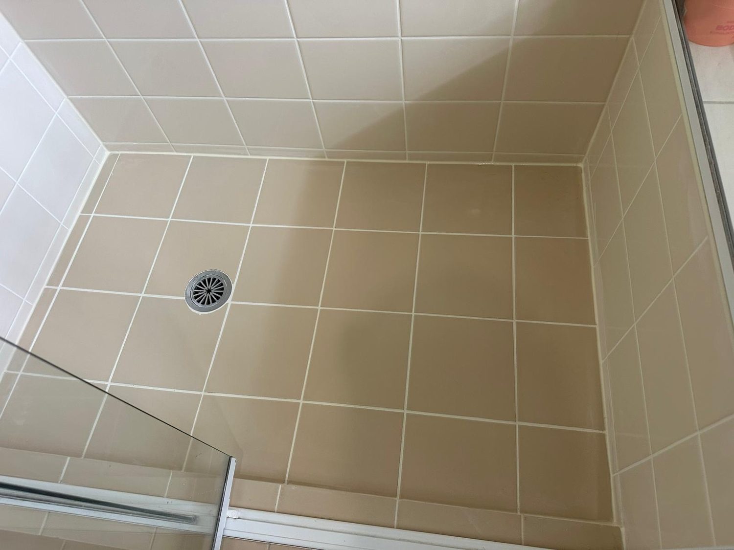 Cream-tiled shower with clean grout after regrouting
