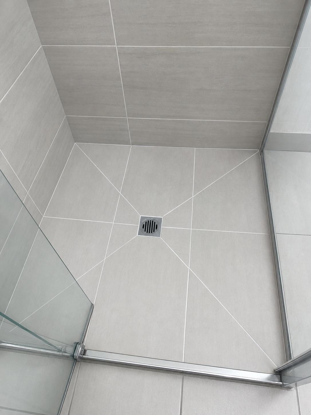 Stone-grey large-format shower floor after regrouting and sealing