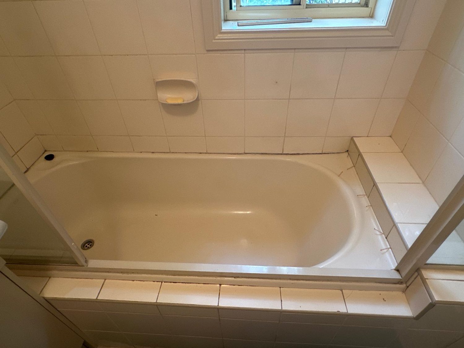 Aged bathroom with bath before regrouting and resealing