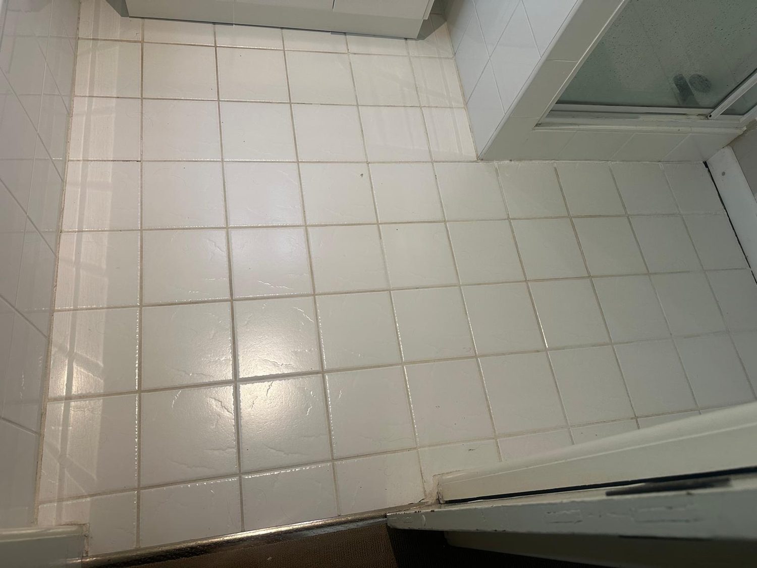 Worn tiled floor with discoloured grout before regrouting