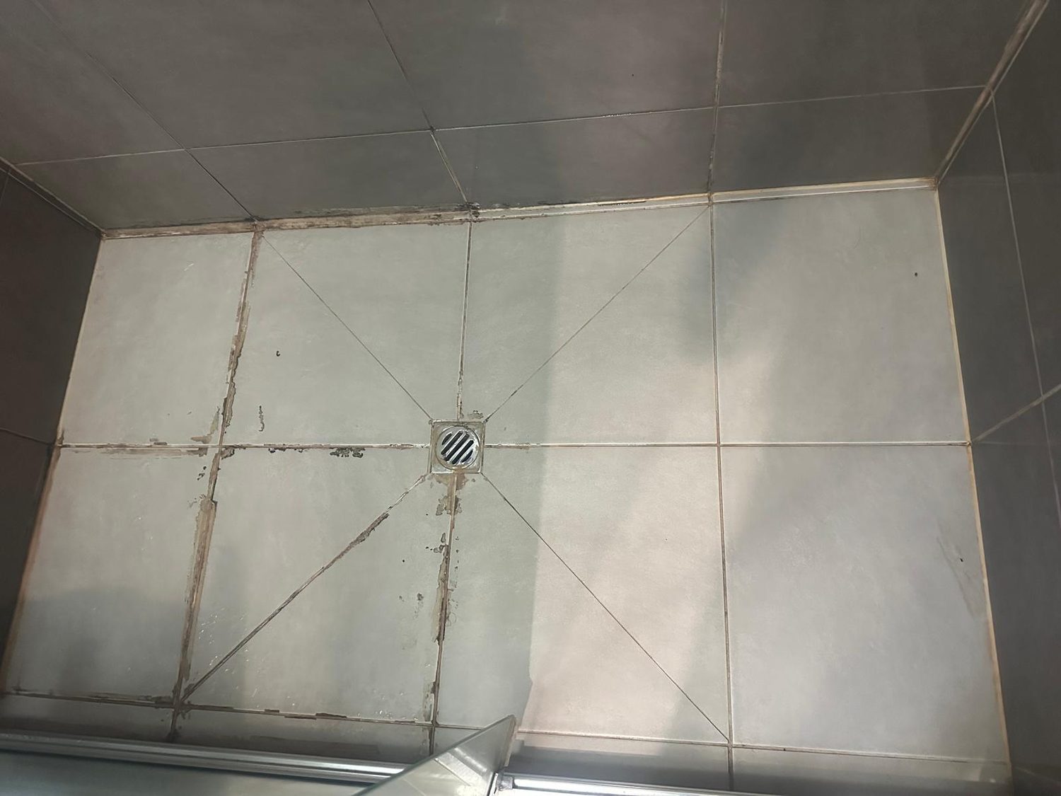 Leaking grey-tiled shower with failed grout before repair